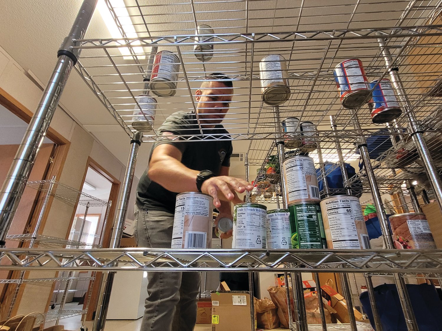 EMPTIED SHELVES: Tyrone “Ty” Smith, Director of Employment and Housing for Operation Stand Down Rhode Island (OSDRI), surveys the organization’s food bank shelves. The group needs help collecting food for the region’s veterans.